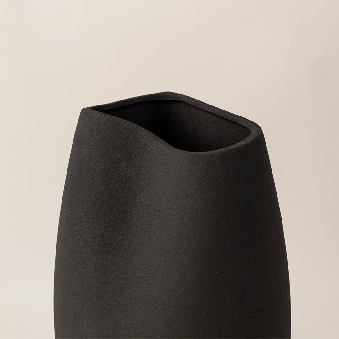 Closeup of black ceramic vase showing matte surface texture and sleek handcrafted curved body for modern artistic appeal.