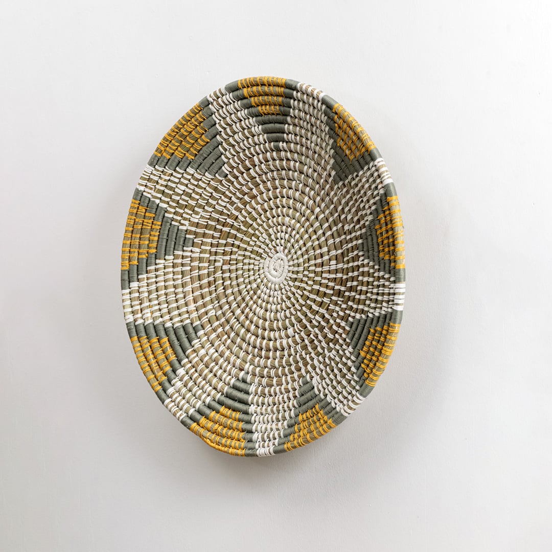 Side profile view of the large woven seagrass wall basket showing its flat disc shape and the texture of the natural coiled fibers.