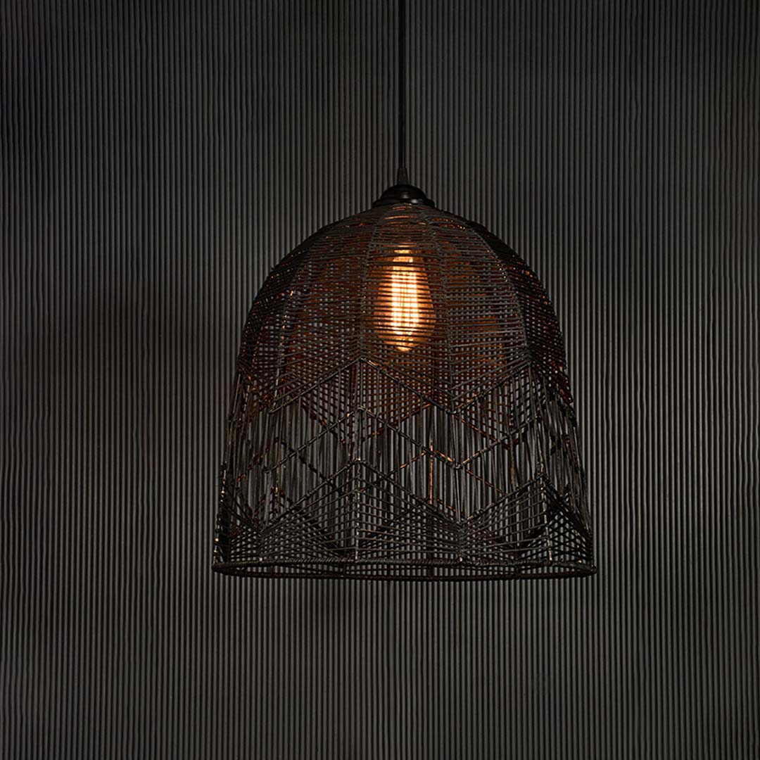 Black woven bamboo pendant lamp glowing softly on white background creating a warm modern ambience.