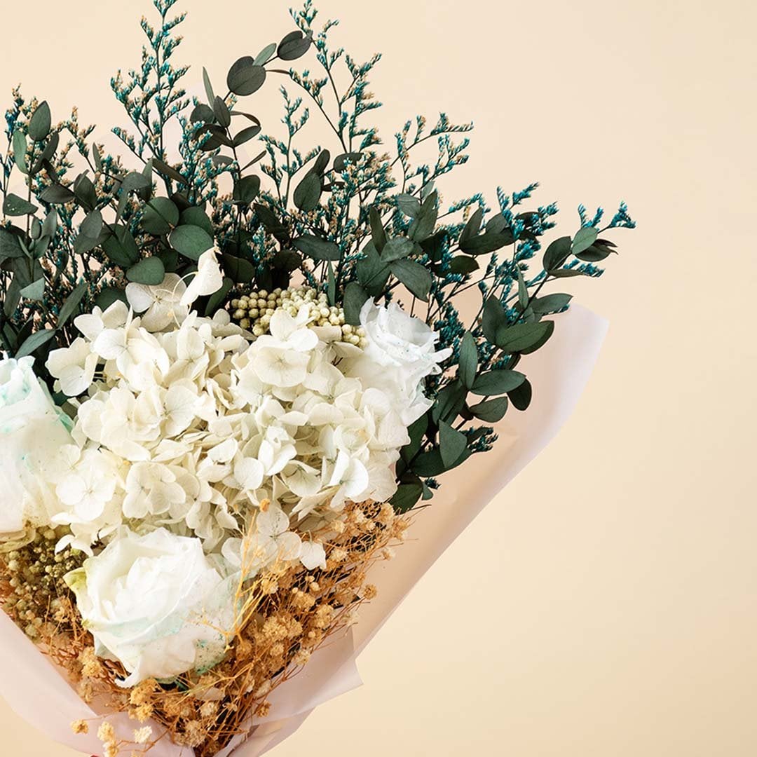 Elegant dried flower bouquet with white infinity rose hydrangea and eucalyptus wrapped with satin ribbon for home decor.