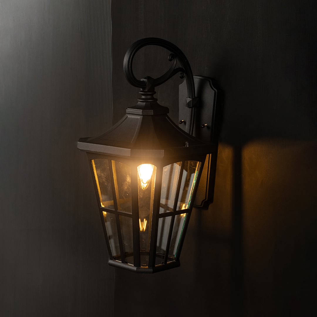 Decorative lantern gate light glowing against a black background for dramatic effect.