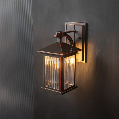 Decorative lantern wall sconce with ribbed glass glowing warmly on a black background.