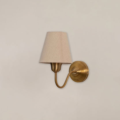 Vintage brass wall sconce with white fabric shade and curved bracket switched off on clean minimal white background.