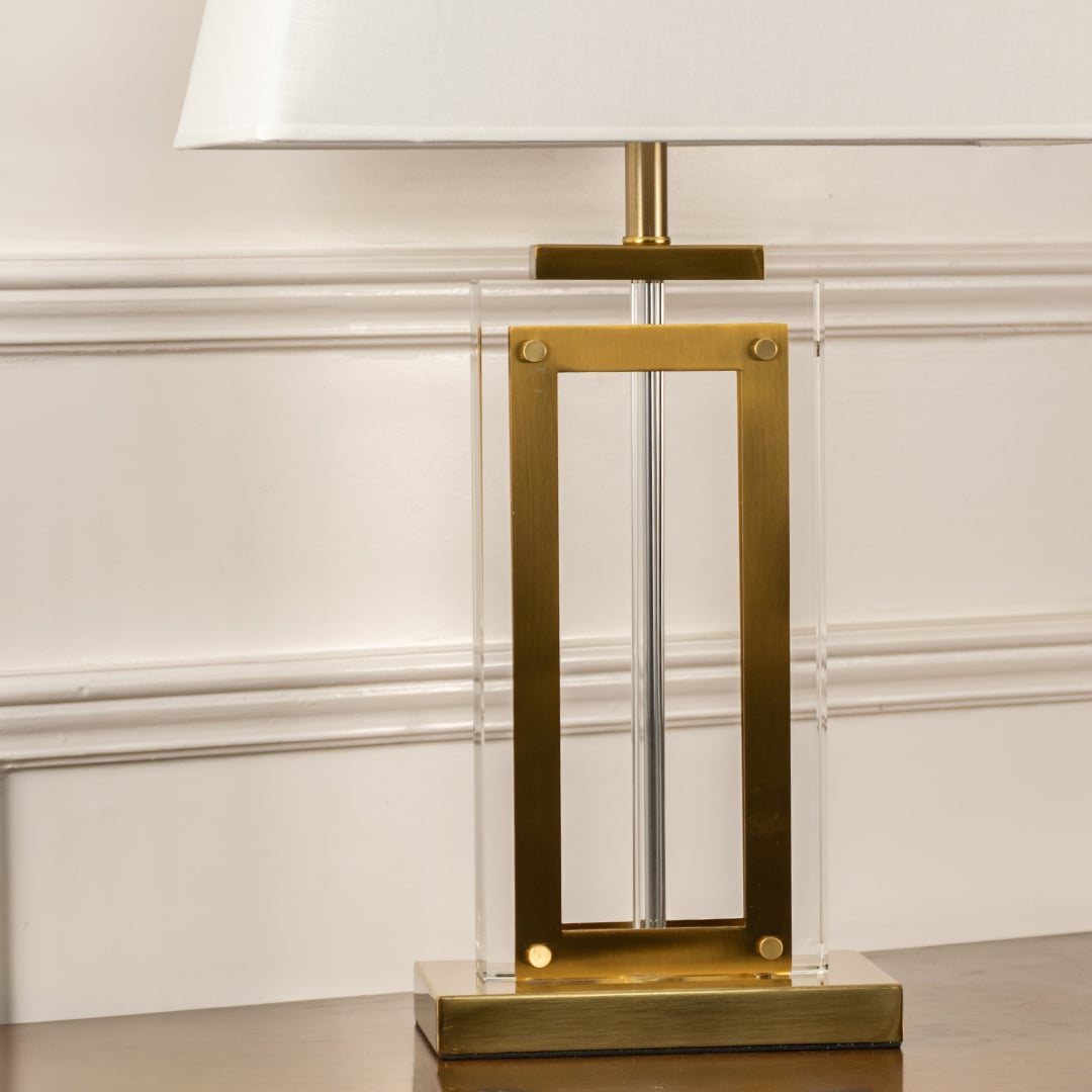 Detailed view of gold table lamp showing the metallic finish  sharp rectangular structure  and textured linen shade.