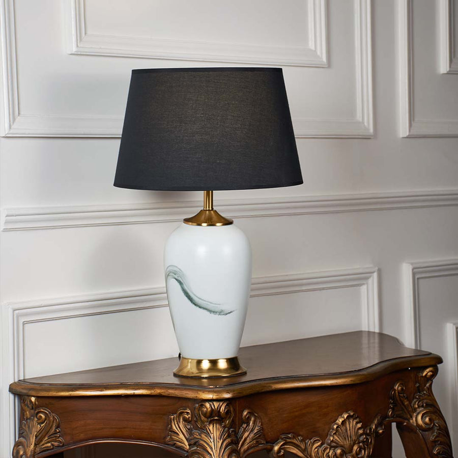 White ceramic table lamp with grey fabric shade and gold accents offering contemporary style and ambient table lighting.