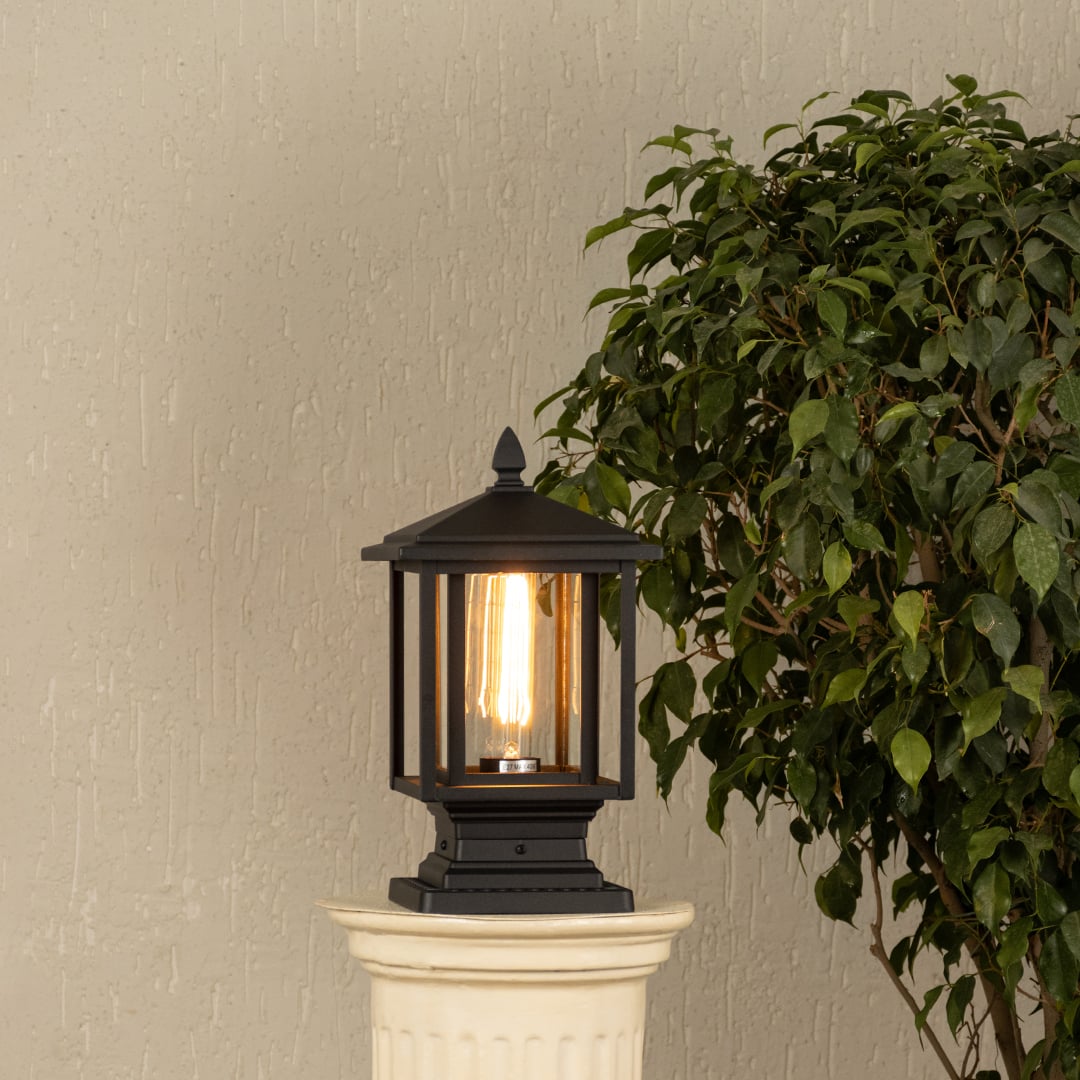 Black metal outdoor post light with ribbed glass Light On placed on a decorative column Lifestyle image patio decor.