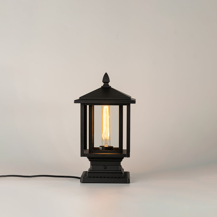 Black outdoor gate light with warm glowing bulb for modern exterior decor styling use.
