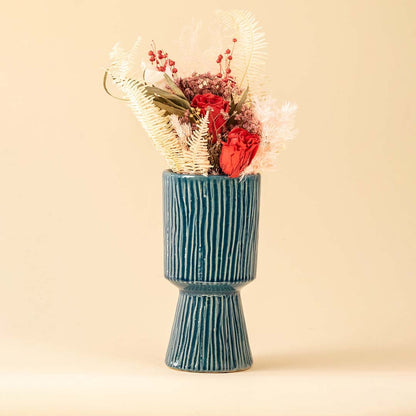 A tall blue textured vase showcased on a clean white background highlighting its vertical line pattern and modern sculpted silhouette.