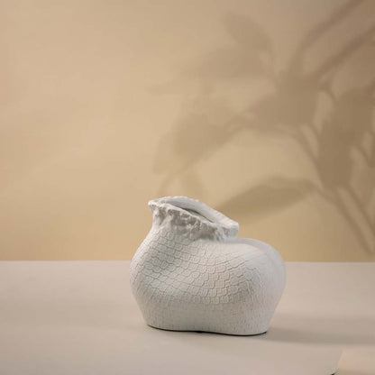 Single white textured ceramic vase with sculptural organic shape and matte finish placed on a plain white surface.
