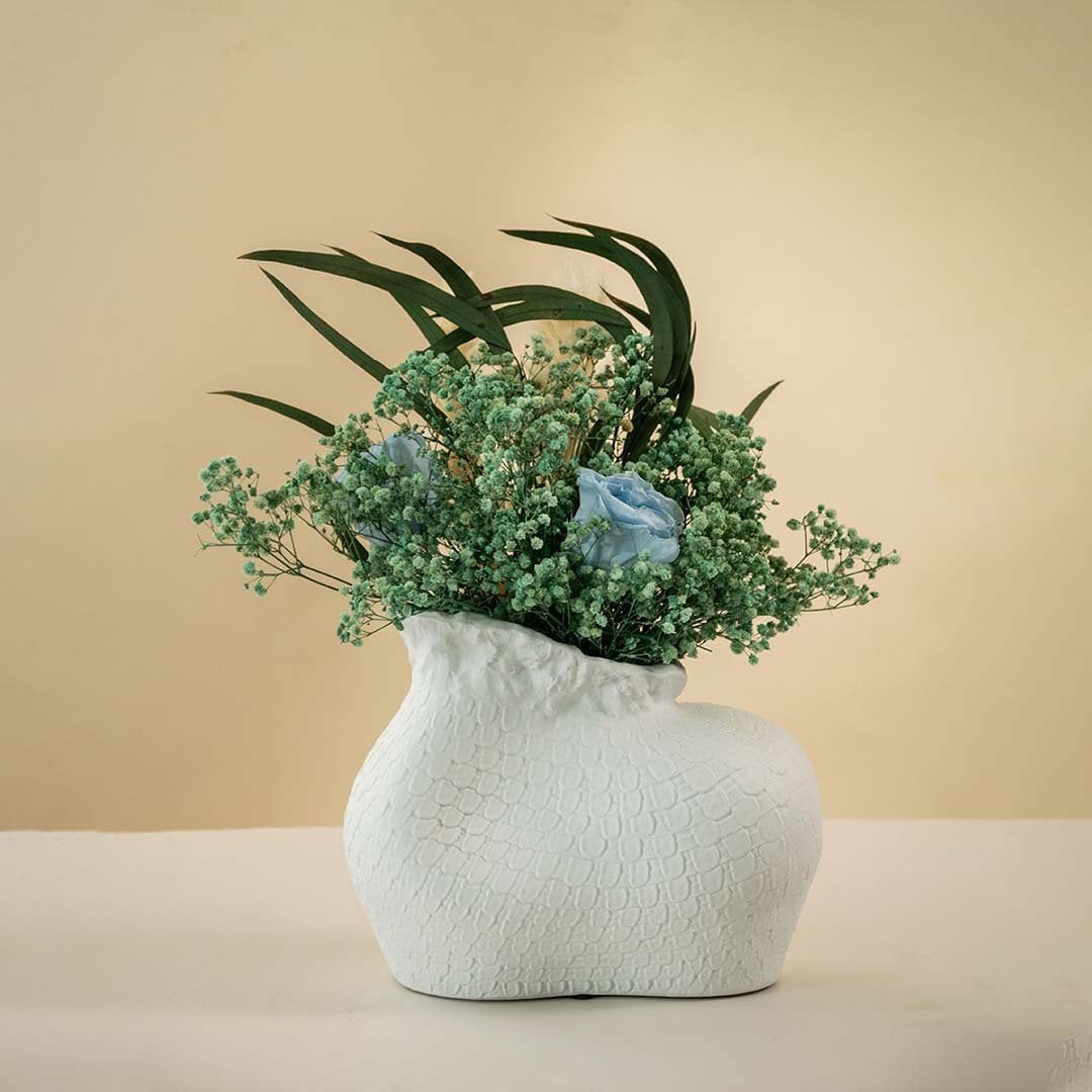 Minimalist white textured ceramic vase with an irregular artistic shape and matte finish placed against a white background.