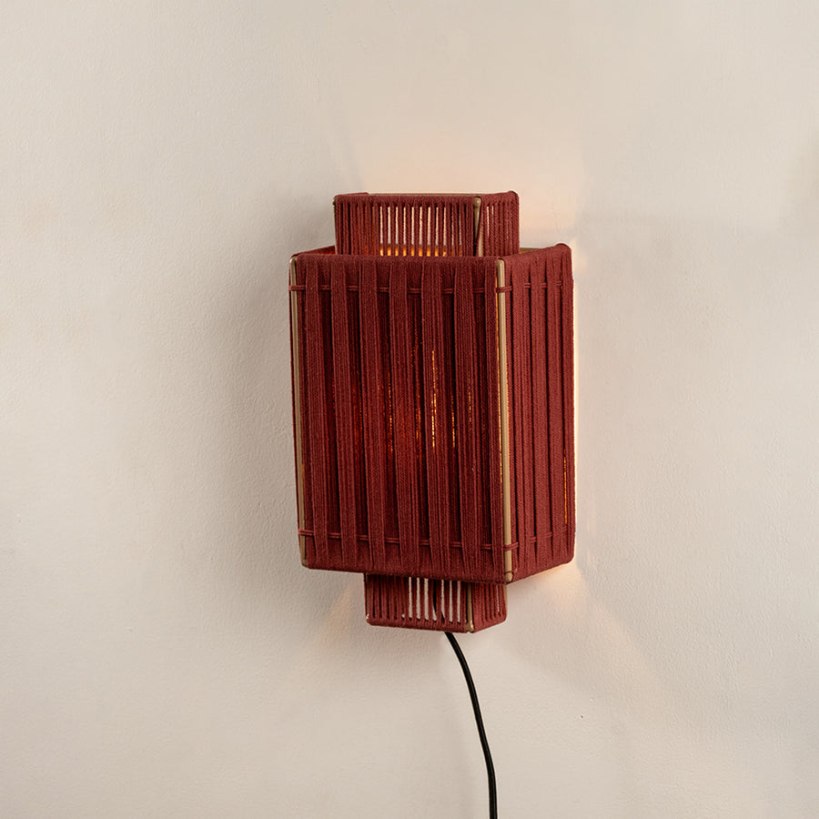 Red textured wall light with rectangular design and warm glow perfect for modern bedroom or hallway wall decor placement.