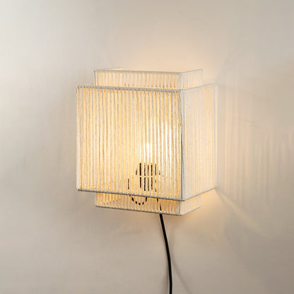 Wall light with pleated fabric shade emitting warm light ideal for bedroom or living room wall decor on clean white background.