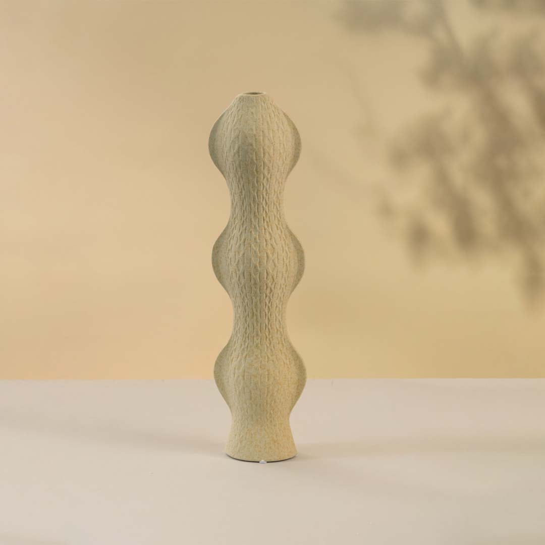 Contemporary beige ceramic vase with curved silhouette and textured surface against white background perfect for adding sophistication to modern home interiors.