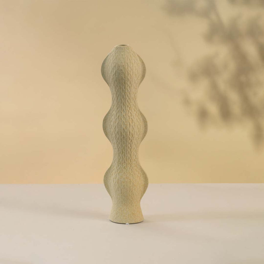 Contemporary beige ceramic vase with curved silhouette and textured surface against white background perfect for adding sophistication to modern home interiors.