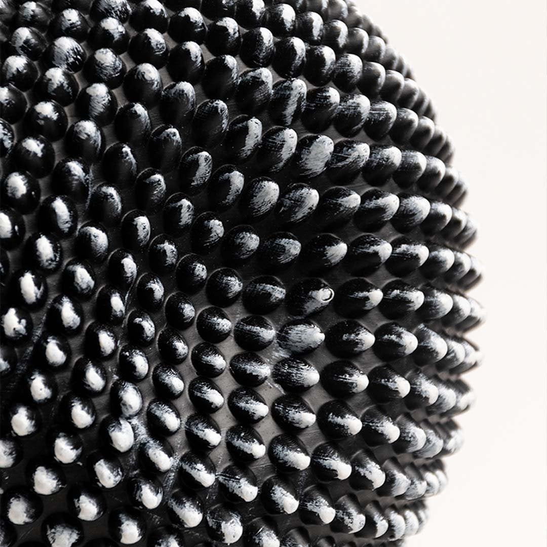 Closeup showing the detailed texture of the black and white sphere sculpture with intricate design.