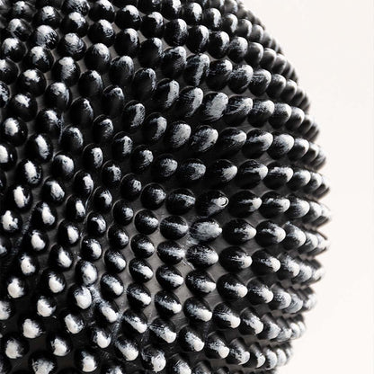 Closeup showing the detailed texture of the black and white sphere sculpture with intricate design.