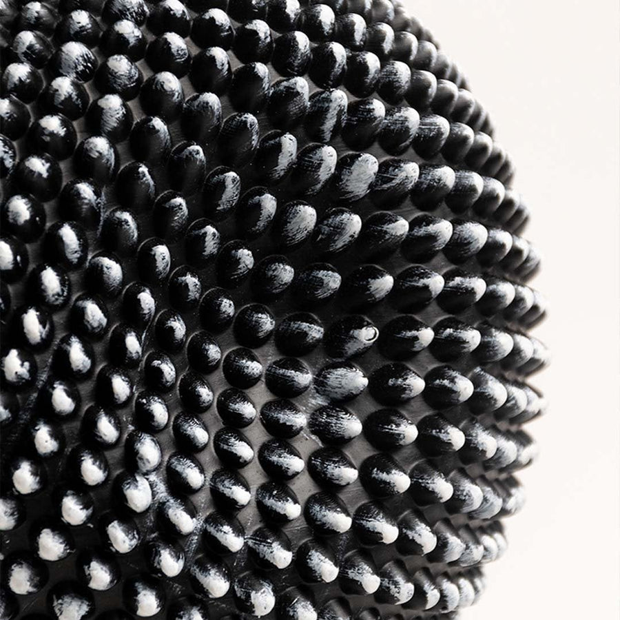 Closeup showing the detailed texture of the black and white sphere sculpture with intricate design.