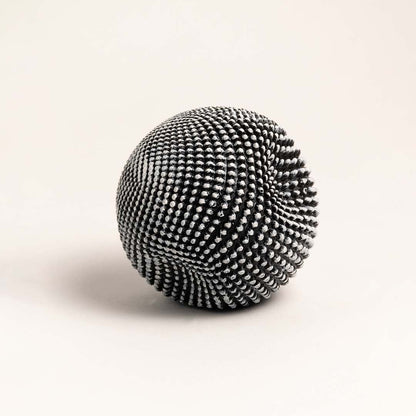 Sculptural black and white ball with intricate texture displayed on a clean white background highlighting its design.