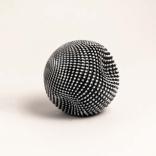 Sculptural black and white ball with intricate texture displayed on a clean white background highlighting its design.