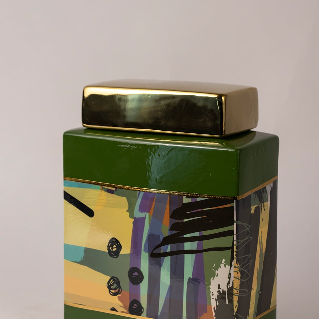 Closeup of abstract ceramic jar showing detailed artwork and smooth glossy finish with golden lid.