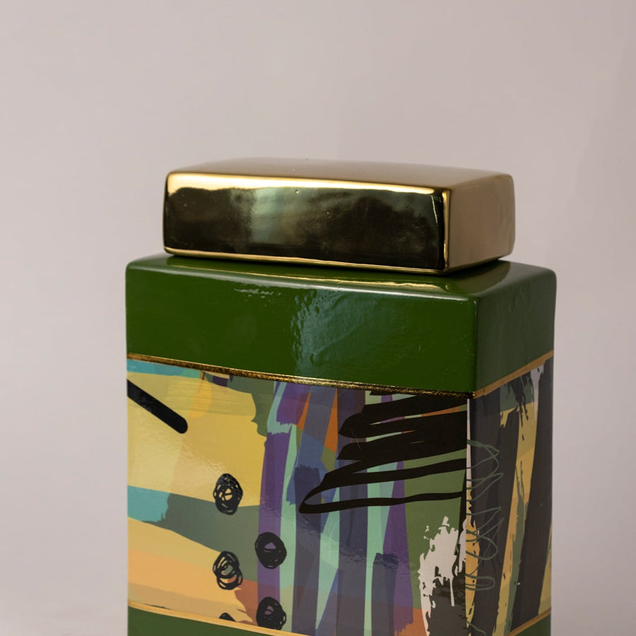 Closeup of abstract ceramic jar showing detailed artwork and smooth glossy finish with golden lid.