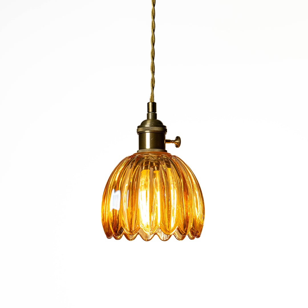 Amber ribbed glass pendant light with antique brass accents creating cozy illumination indoors.