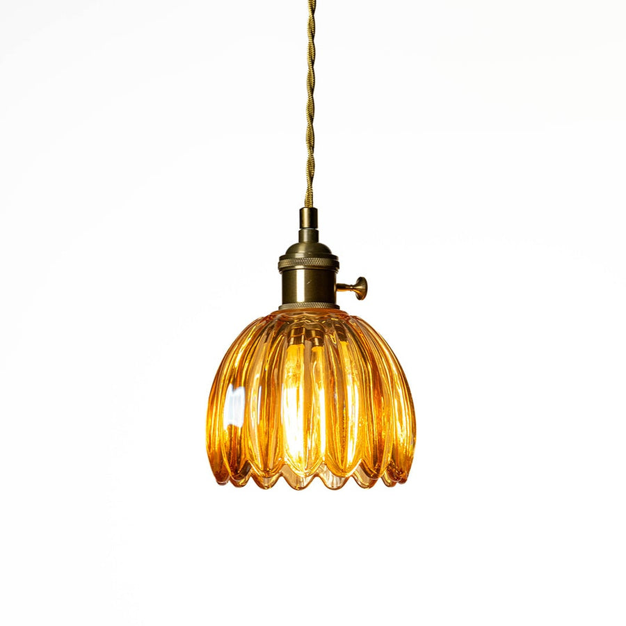 Amber ribbed glass pendant light with antique brass accents creating cozy illumination indoors.