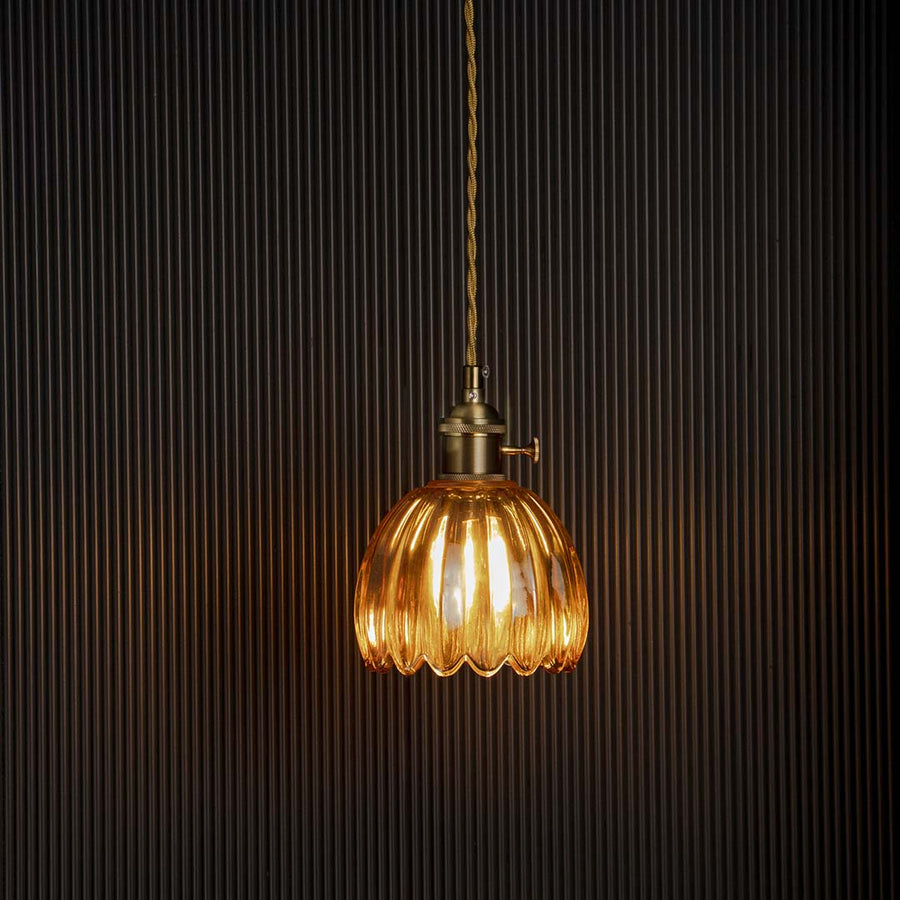 Amber ribbed glass pendant light glowing warmly on black background adding elegance to bedroom dining and interiors.