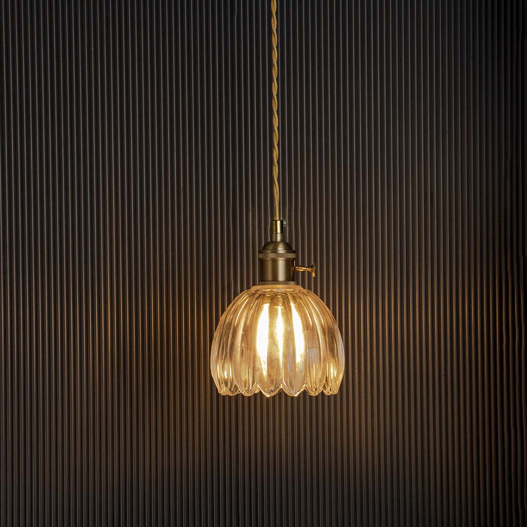 Clear ribbed glass pendant light glowing beautifully on black background adding elegance to modern interiors.