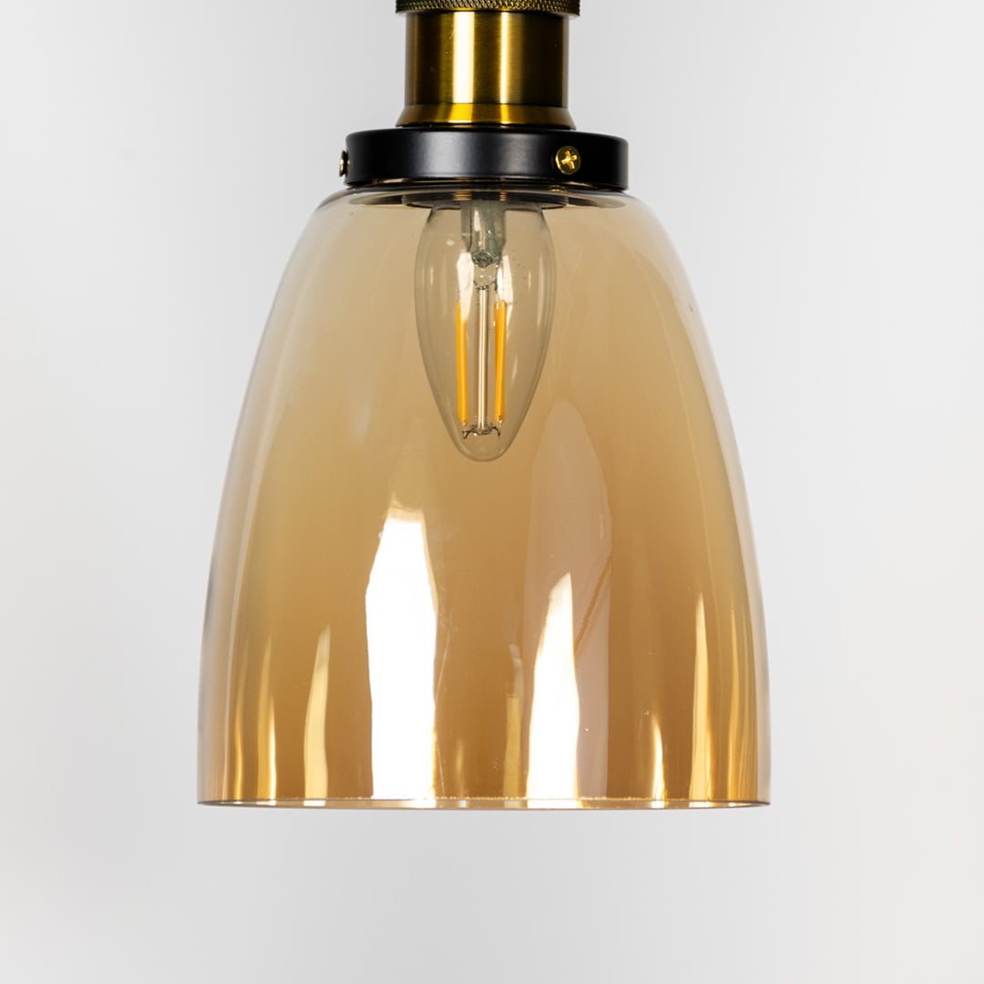 Closeup of gold glass pendant light with brass and black holder showing elegant reflective finish.