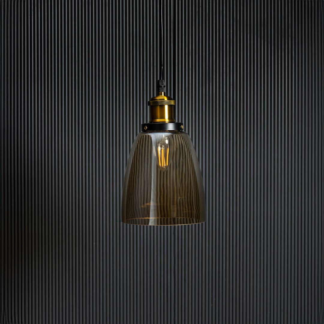 Gold glass pendant light with brass and black holder in stylish design turned off against black background.