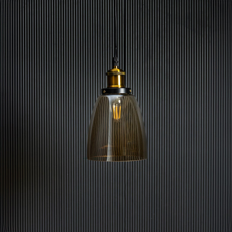 Gold glass pendant light with brass and black holder in stylish design turned off against black background.