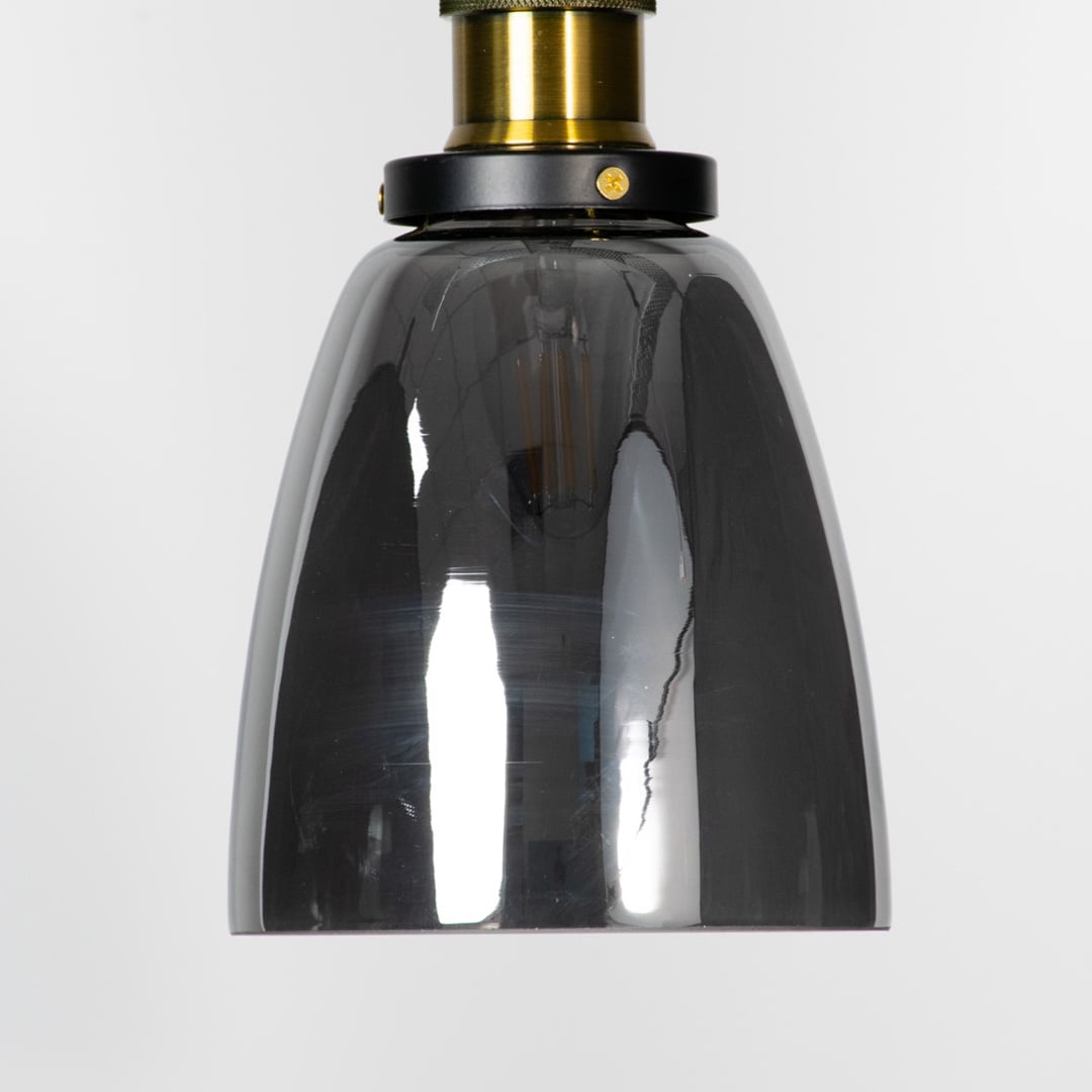 Closeup of smoked glass pendant light with brass and black holder showcasing elegant modern design.