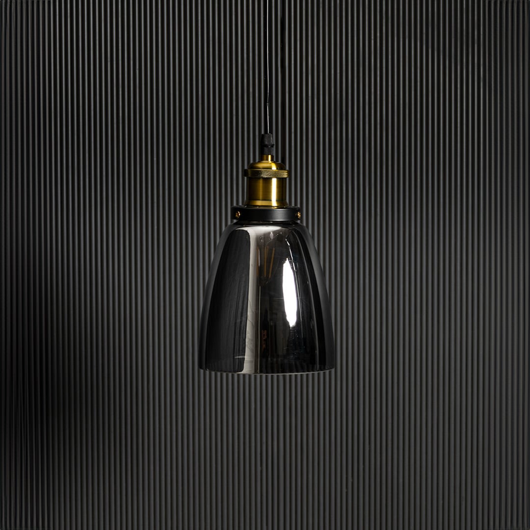 Smoked glass pendant light with brass and black holder in stylish design turned off against black background.