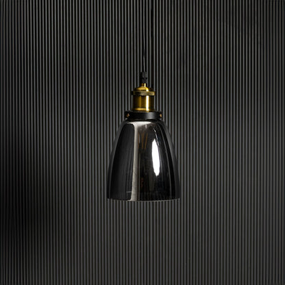 Smoked glass pendant light with brass and black holder in stylish design turned off against black background.