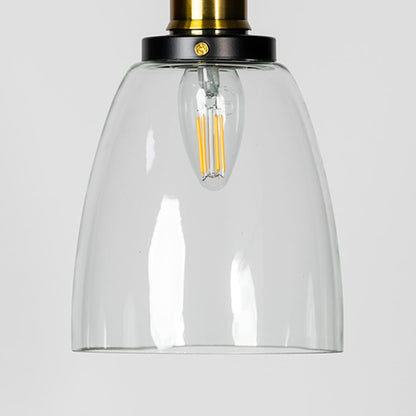 Closeup of clear glass pendant light with brass and black holder showcasing modern minimalist design.