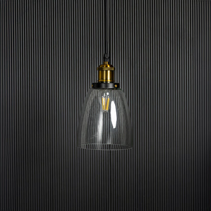 Clear glass pendant light with brass and black holder in modern design turned off on plain white background.