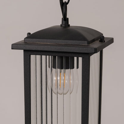 Closeup of black metal hanging lantern showcasing ribbed glass texture and warm bulb detail for outdoor home decor lighting.