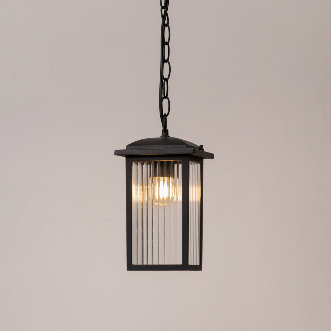 Modern outdoor pendant light in black metal with glass panels for entrance or patio decor lighting white background.