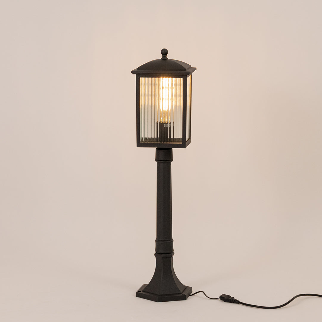 Black outdoor garden light with warm glowing ribbed panels for elegant exterior decor styling use.