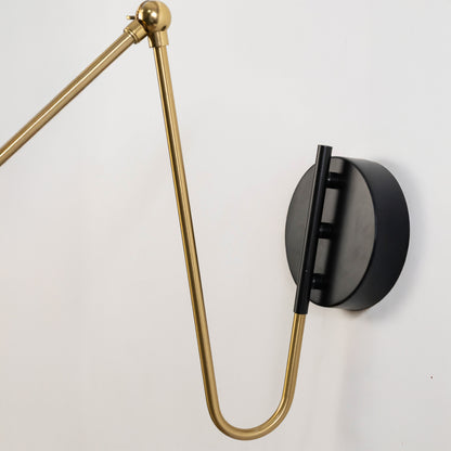 Adjustable wall light with gold arm and black mount on neutral background modern task lighting ideal for bedroom and study decor.