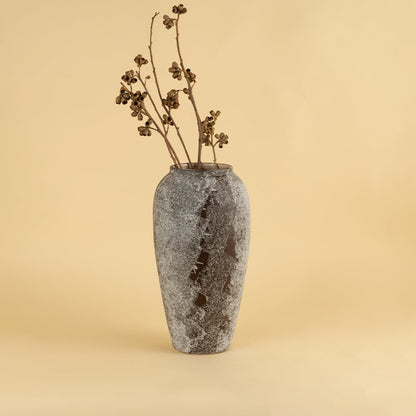 Tall rustic ceramic vase in grey brown textured finish styled with dry stems for modern home interior decoration.