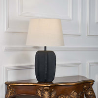 Matte black ceramic table lamp with fabric beige shade turned off on white background highlighting its bold modern silhouette and premium craftsmanship.