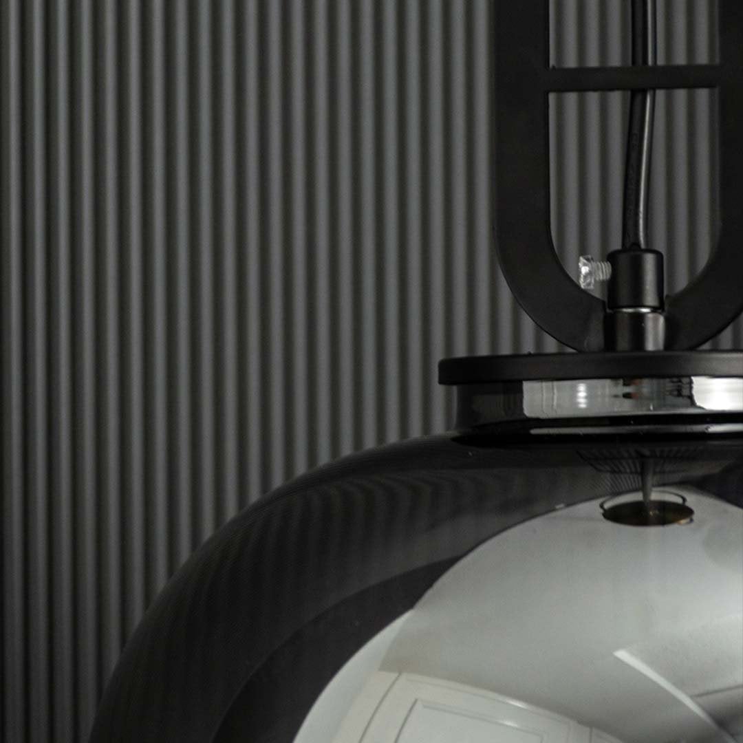 A closeup of the smoked glass pendant light highlighting its warm illuminated filament bulb and reflective smooth curved glass design.