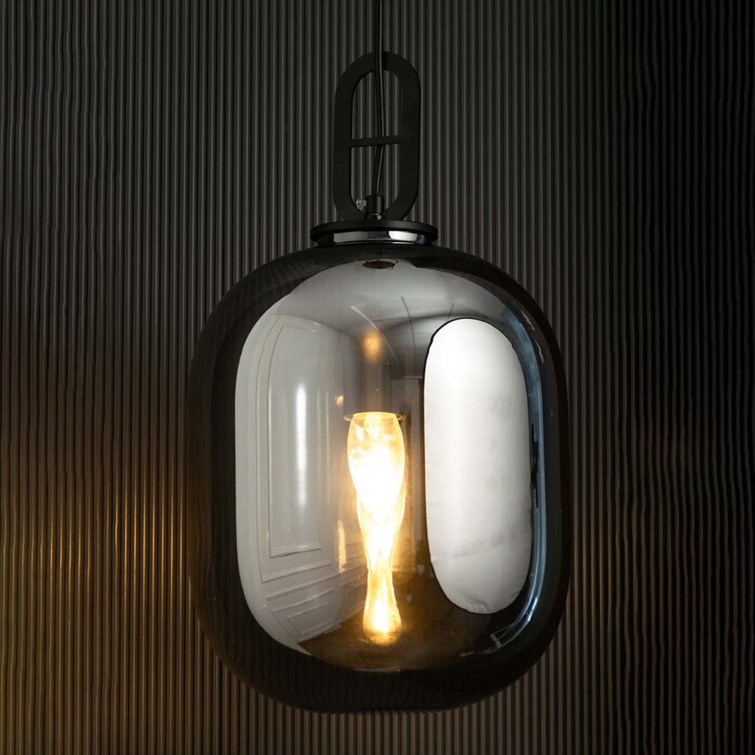 A contemporary smoked glass pendant light glowing warmly against a dark textured background creating a rich ambient lighting effect for modern interiors.