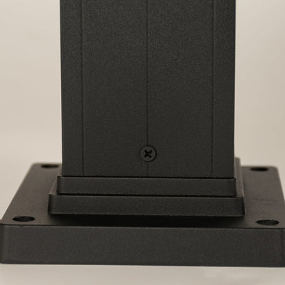 A detailed closeup focusing on the glowing bulb inside the ribbed glass panel of the outdoor bollard light showing warm illumination and refined craftsmanship.