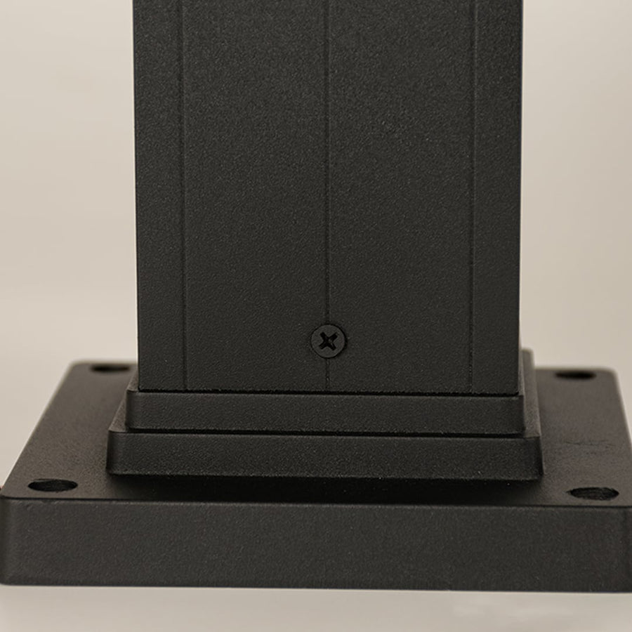 A detailed closeup focusing on the glowing bulb inside the ribbed glass panel of the outdoor bollard light showing warm illumination and refined craftsmanship.