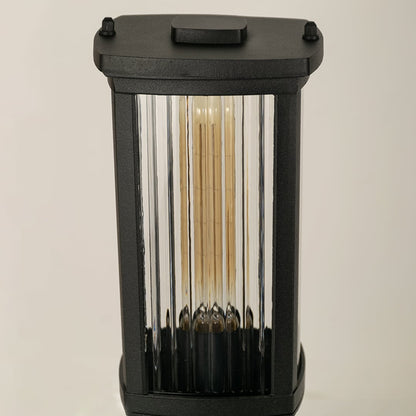 A closeup view of the outdoor bollard light highlighting the ribbed clear glass panels and metallic black frame with detailed texture and clean modern lines.