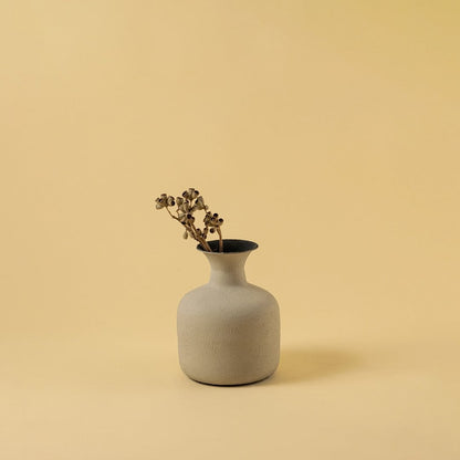 A calm interior scene shows a beige textured vase styled with dried stems bringing a warm earthy aesthetic that enhances the simplicity of the soft background.