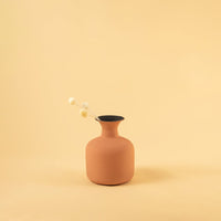 Terracotta matte finish vase styled with dried botanical stems adding a warm natural touch to a calm beige interior setting with soft light enhancing the decor.